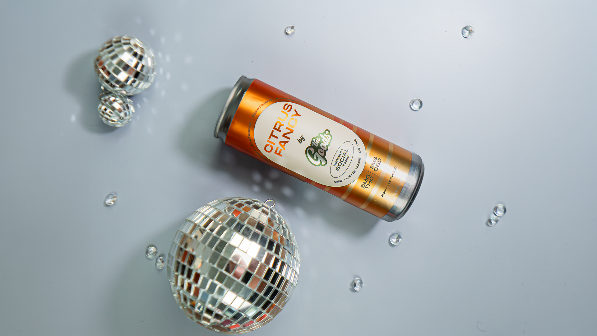 Citrus Fancy Social Tonic in front of a white background laying next to a disco ball