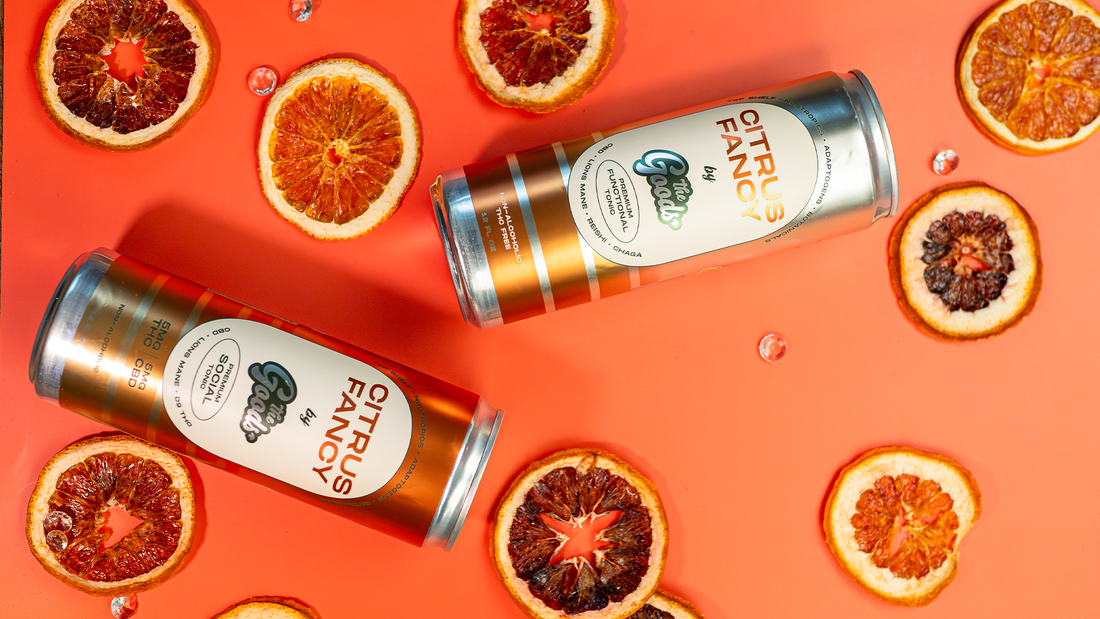 Citrus fancy social tonic and functional tonic in front of an orange background next to orange slices scattered about