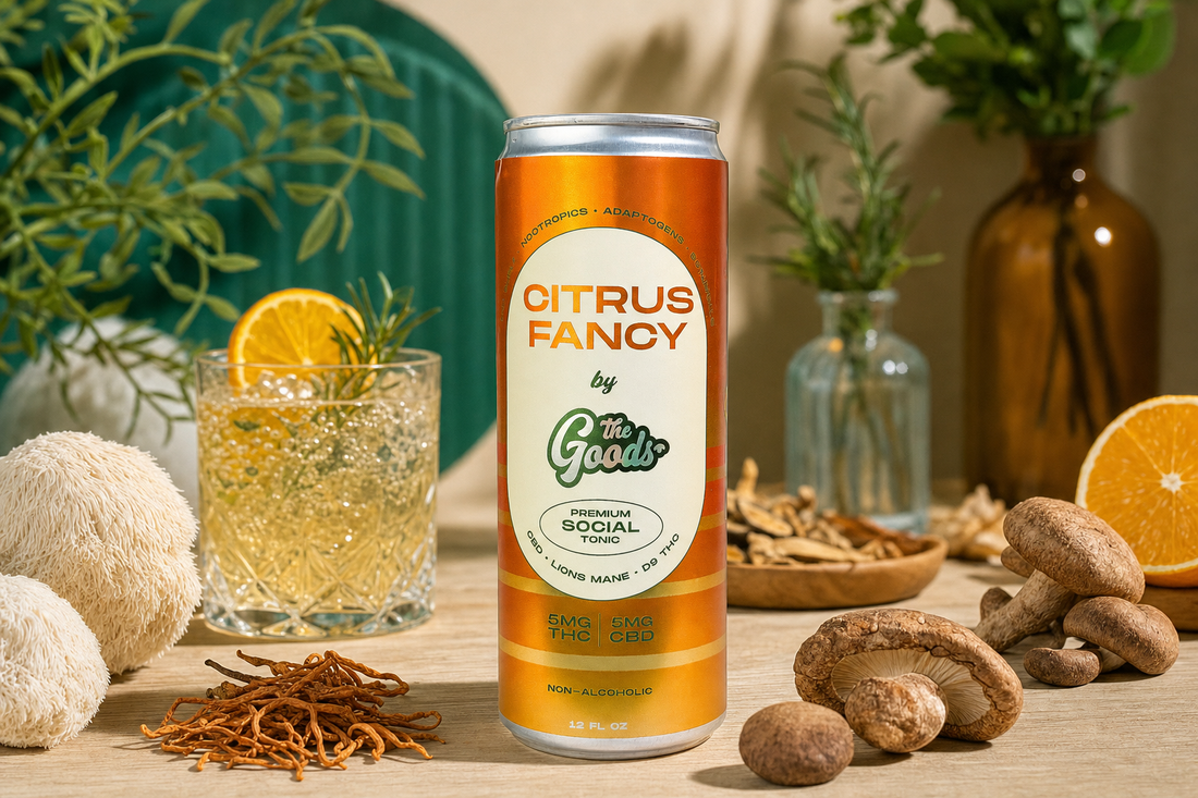 Orange Citrus Fancy tonic can surrounded by mushrooms, herbs, orange slice, and a poured cocktail on wood.