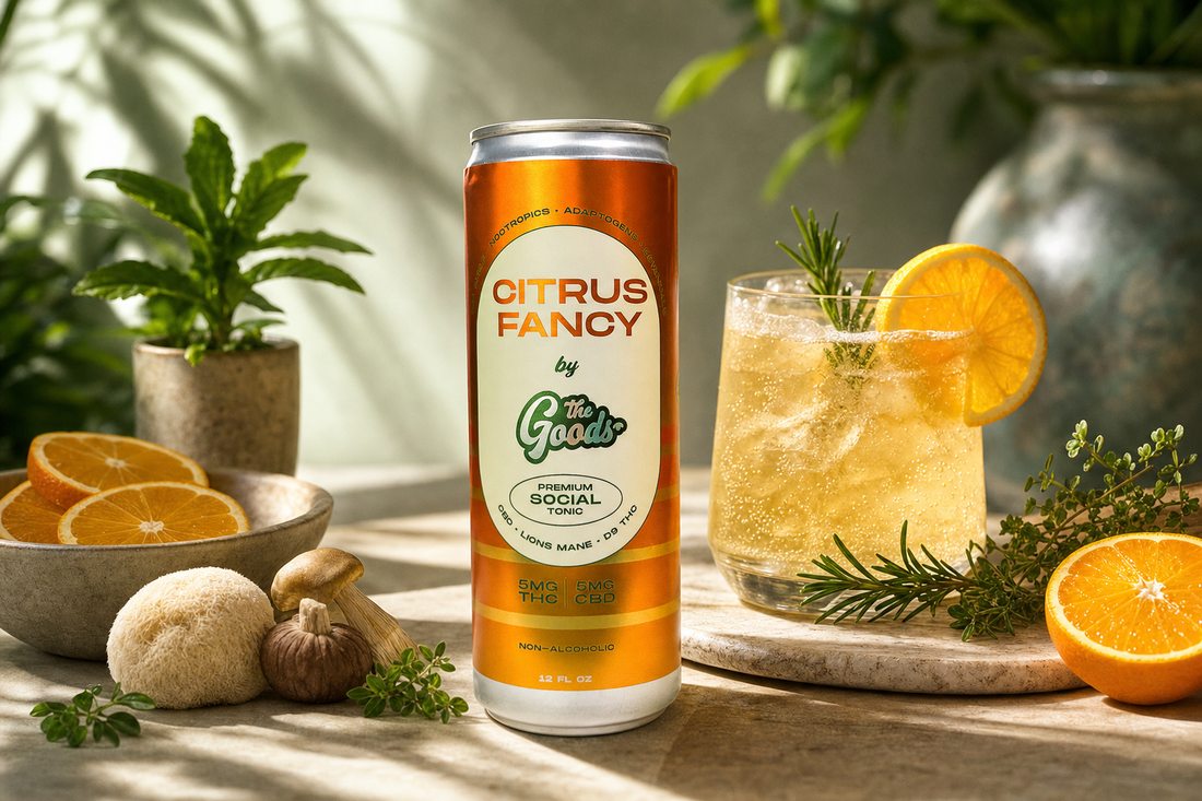 Citrus Fancy THC/CBD social tonic can beside an iced drink garnished with orange and rosemary, mushrooms and citrus nearby.