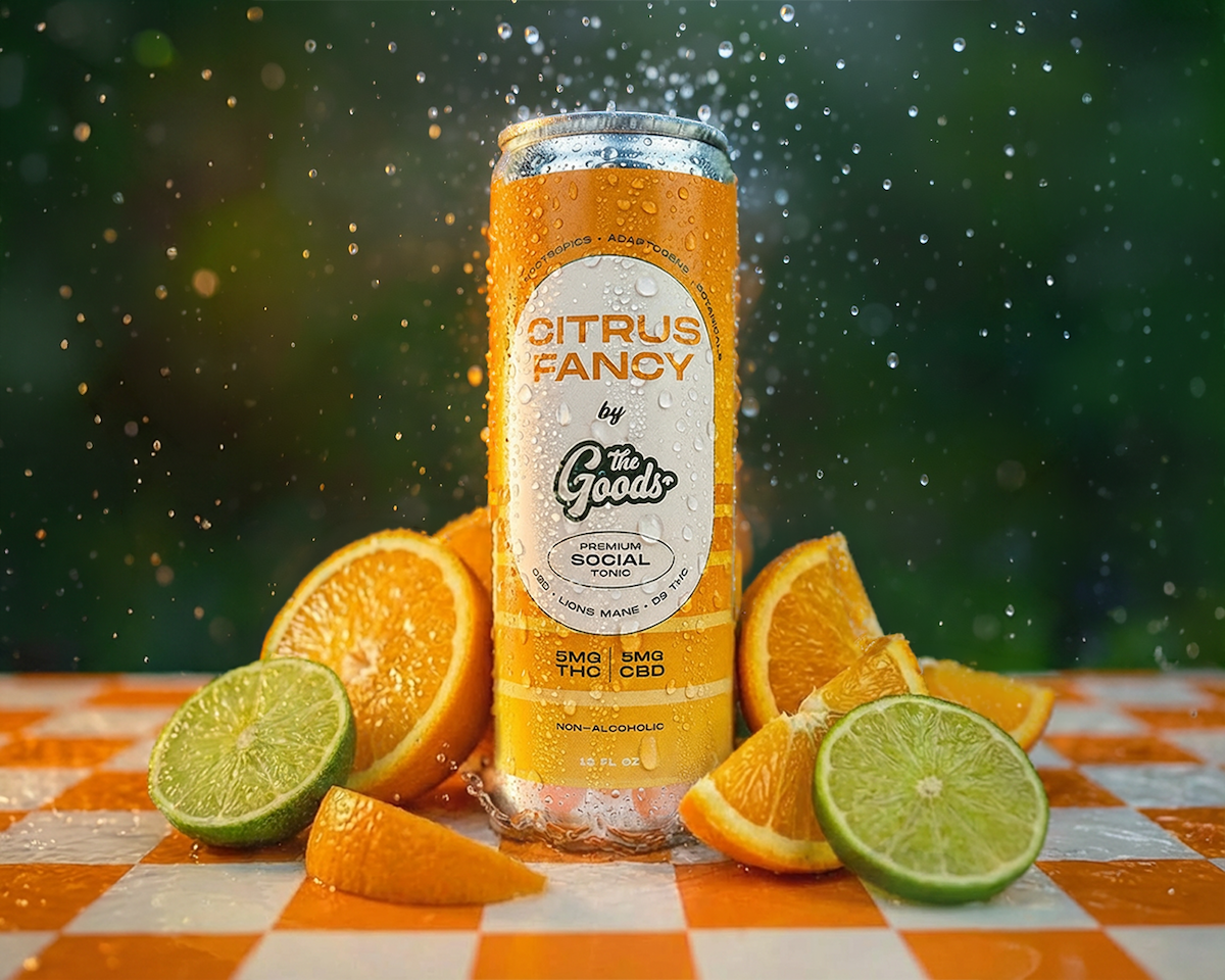 Orange can of 'Citrus Fancy' by 'The Goods' with oranges and limes on a checkered tablecloth.